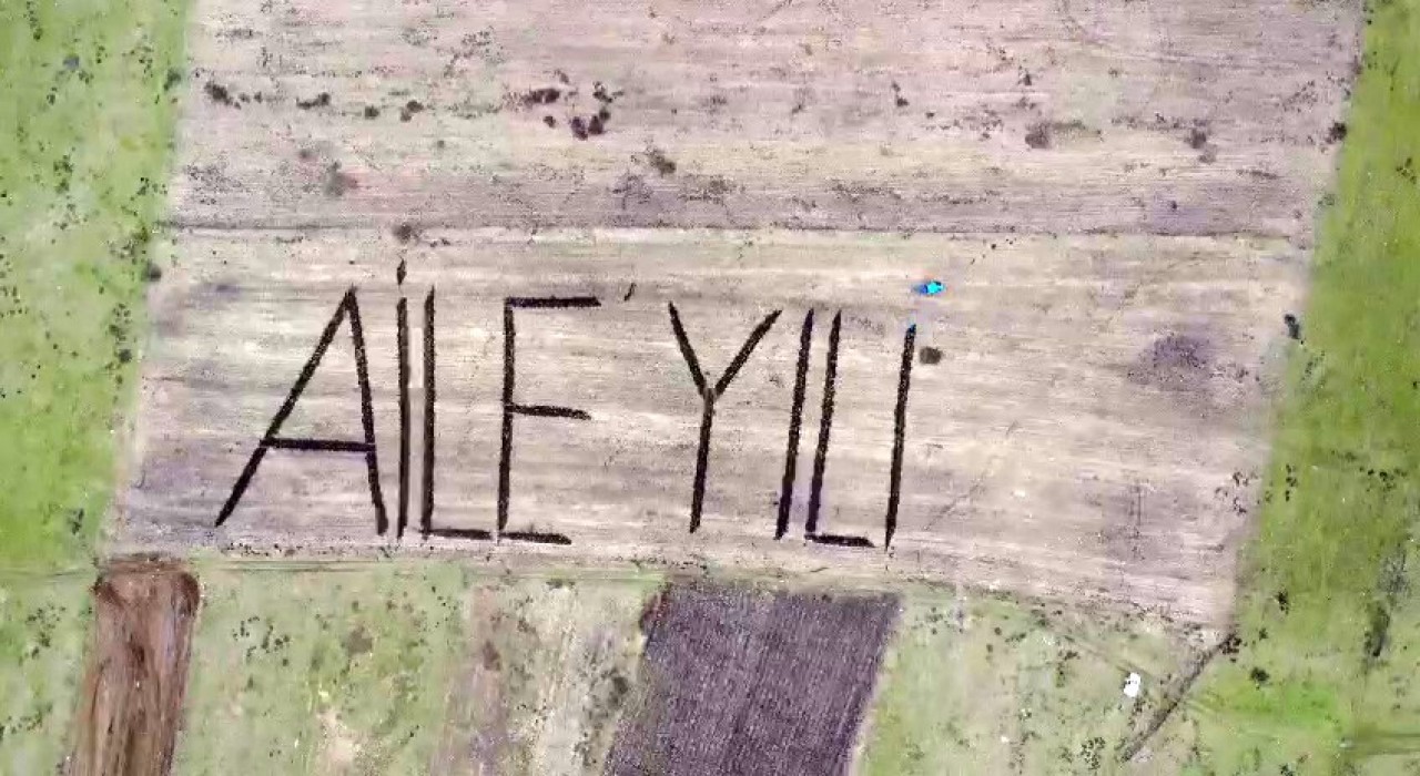 Tarlasına traktörüyle Aile Yılı yazdı