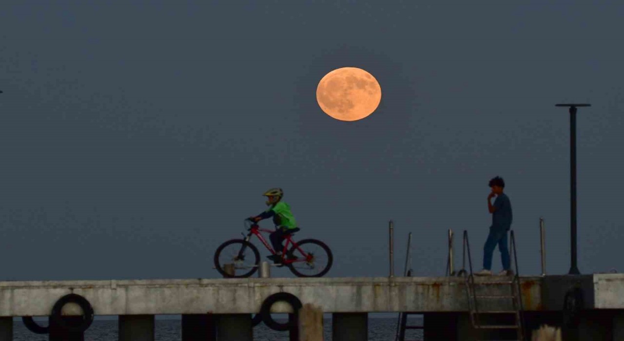 Dolunay ile insanların siluetleri aynı karede