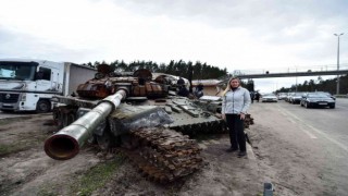 Ukraynalı sivillerden imha edilen Rus tankının önünde zafer pozu