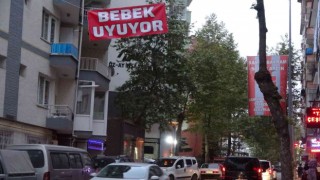 Araç gürültüsünden uyuyamayan bebeği için caddeye Bebek uyuyor afişi astı