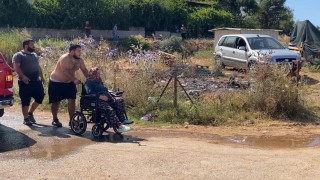 Evine yaklaşan alevlerden kurtarılan kadın tekerlekli sandalyeyle bölgeden uzaklaştırıldı