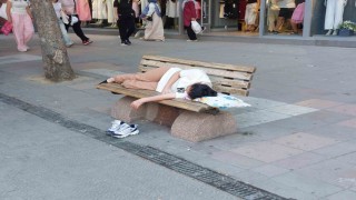 Sıcaktan bunalan genç gölgelik bankta yastıkla beraber uyudu