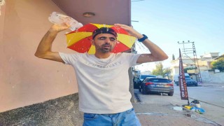 Aşırı sıcaklar nedeniyle kafasına taktığı şemsiye ile geziyor