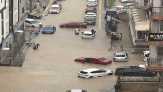 Yağmurda mahsur kalan motosikletli çareyi otomobilin üzerine çıkmakta buldu