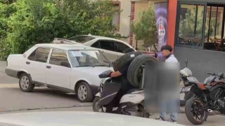 Otomobil lastiğini boynuna asan kuryenin ilginç taşıma yöntemi kameraya yansıdı